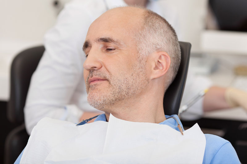 a dental patient sitting in the procedure chair, relaxed and ready for his dental procedure because he has been administered sedation dentistry.