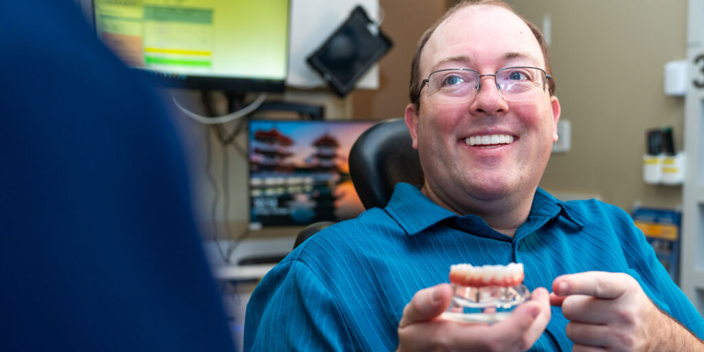 Patient holding up model of full dental arches