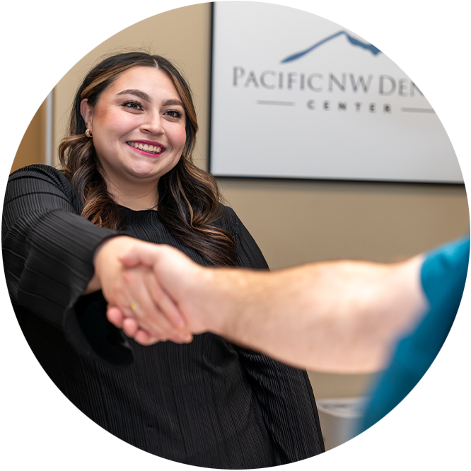 Team member shaking patients hand greeting them into dental office